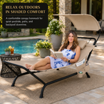 Woman relaxing on a navy chaise lounger with canopy shade beside a pool
