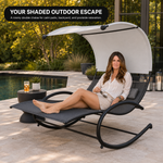 Woman relaxing on a navy chaise lounger with canopy shade beside a pool