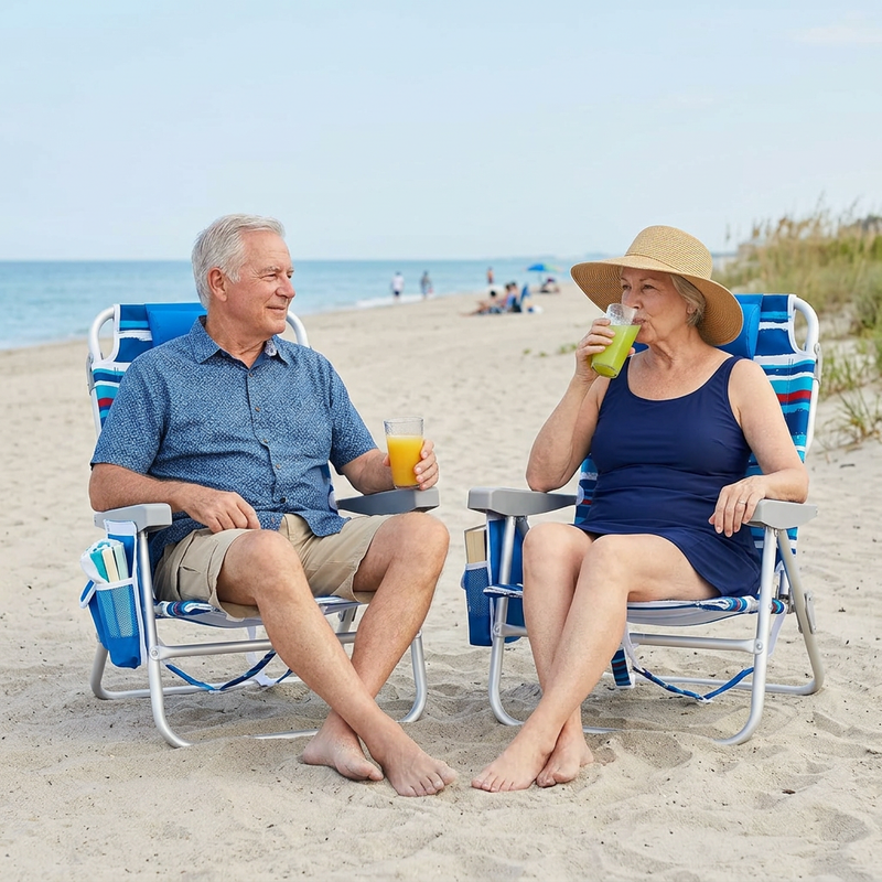Two people relaxing in matching light blue stripe backpack beach chairs on the sand, each reclined with a drink in hand and the ocean in the background