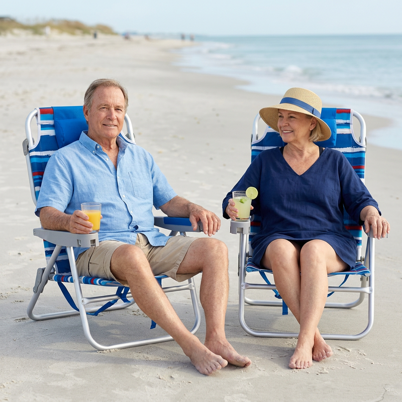 Two people relaxing in matching light blue stripe backpack beach chairs on the sand, each reclined with a drink in hand and the ocean in the background