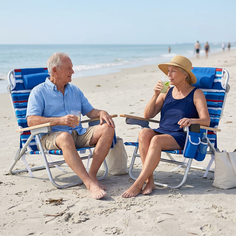 Two people relaxing in matching light blue stripe backpack beach chairs on the sand, each reclined with a drink in hand and the ocean in the background