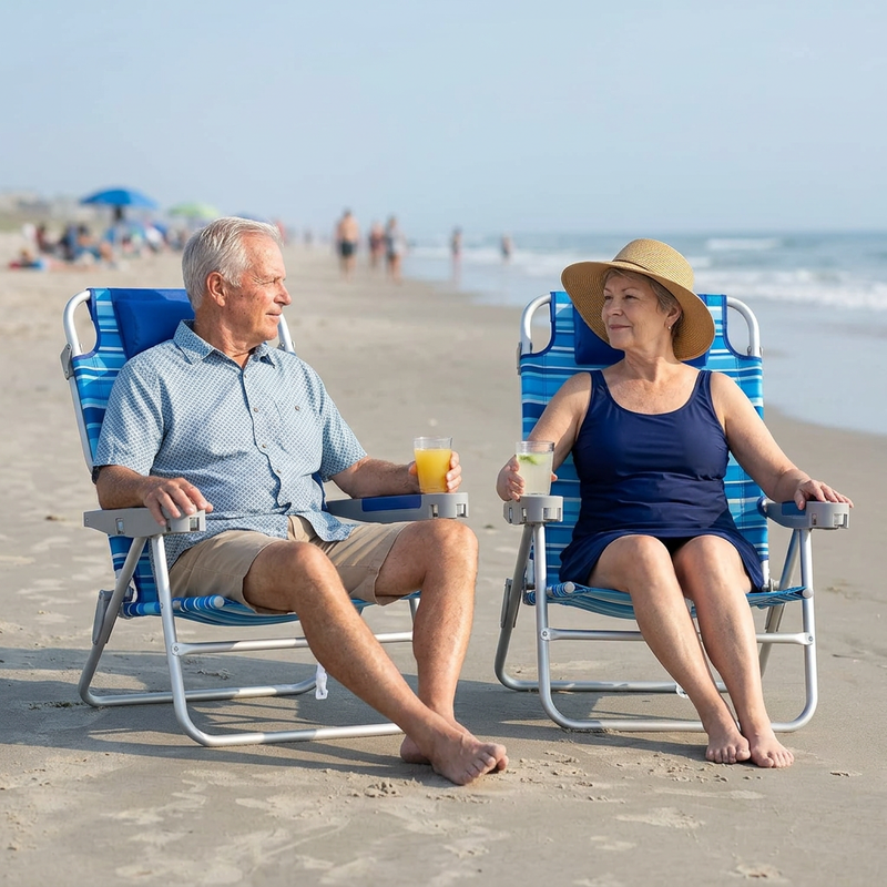 Two people relaxing in matching light blue stripe backpack beach chairs on the sand, each reclined with a drink in hand and the ocean in the background