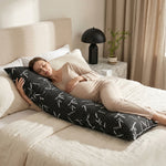 Woman side-sleeping hugging the bamboo memory foam pillow against a dark wood headboard