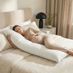 Woman side-sleeping hugging the bamboo memory foam pillow against a dark wood headboard