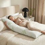 Woman side-sleeping hugging the bamboo memory foam pillow against a dark wood headboard
