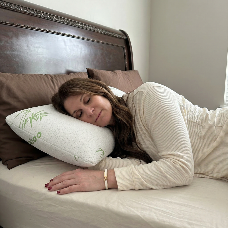 Woman side-sleeping hugging the bamboo memory foam pillow against a dark wood headboard