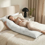 Woman side-sleeping hugging the bamboo memory foam pillow against a dark wood headboard