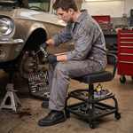 Mechanic seated on the yellow rolling stool performing a front brake job in a home garage