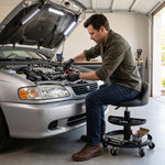 Mechanic seated on the yellow rolling stool performing a front brake job in a home garage