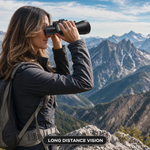 Woman using high-powered binoculars to view a mountain landscape at sunset