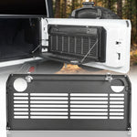 Two-tier tailgate table mounted on a vehicle rear door holding fuel cans and camp gear