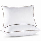 Two down alternative pillows with brown piping and a subtle damask pattern, stacked on a white background