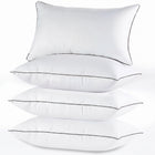Two down alternative pillows with brown piping and a subtle damask pattern, stacked on a white background