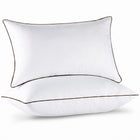 Two down alternative pillows with brown piping and a subtle damask pattern, stacked on a white background