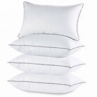 Two down alternative pillows with brown piping and a subtle damask pattern, stacked on a white background