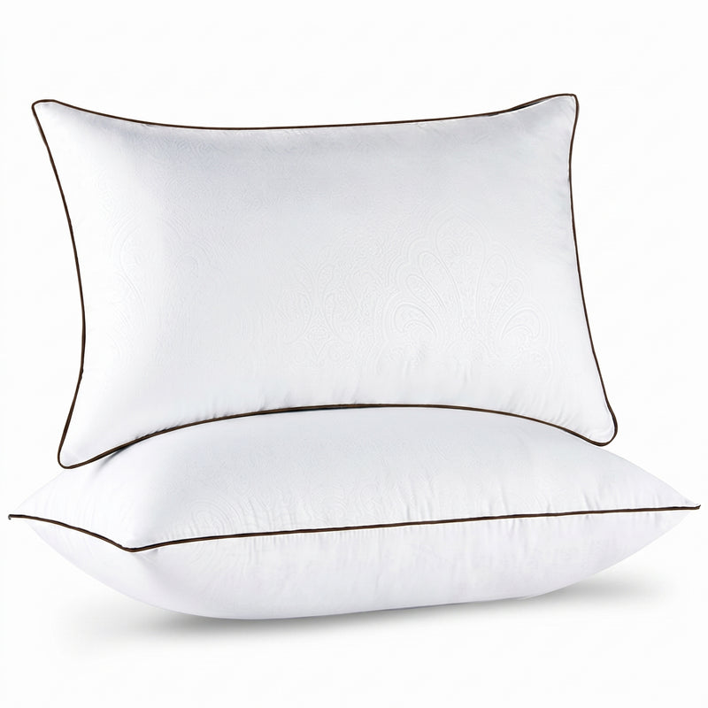 Two down alternative pillows with brown piping and a subtle damask pattern, stacked on a white background
