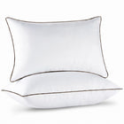 Two down alternative pillows with brown piping and a subtle damask pattern, stacked on a white background