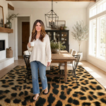 Woman standing beside the faux cowhide cow print area rug showing real-room scale