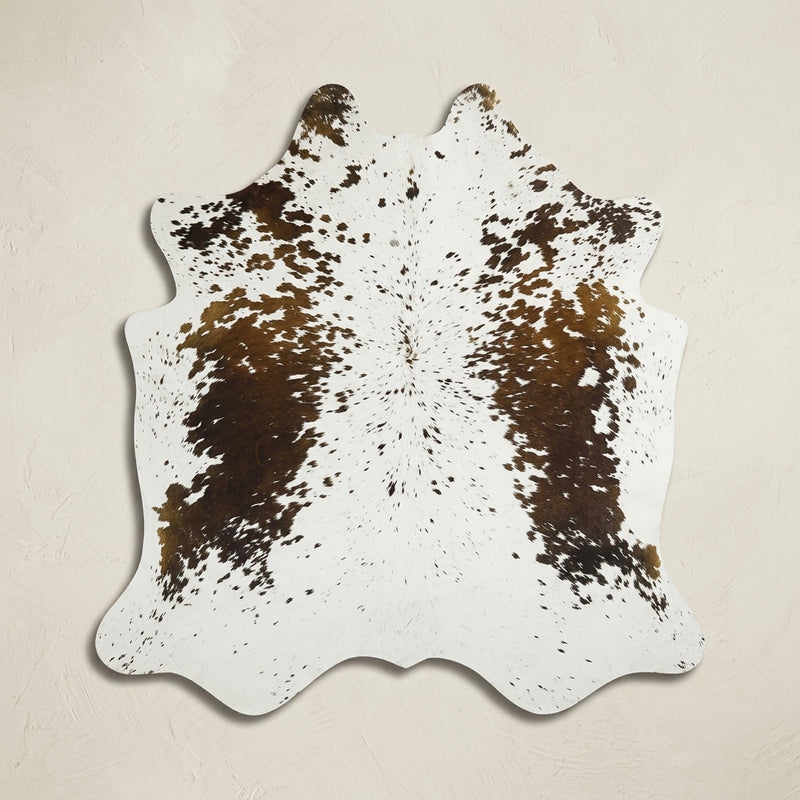 Faux cowhide rug in cow print styled under a leather sofa in a modern living room
