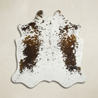 Faux cowhide rug in cow print styled under a leather sofa in a modern living room