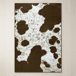 Faux cowhide rug in cow print styled under a leather sofa in a modern living room