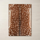 Faux cowhide rug in cow print styled under a leather sofa in a modern living room
