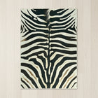 Faux cowhide rug in cow print styled under a leather sofa in a modern living room