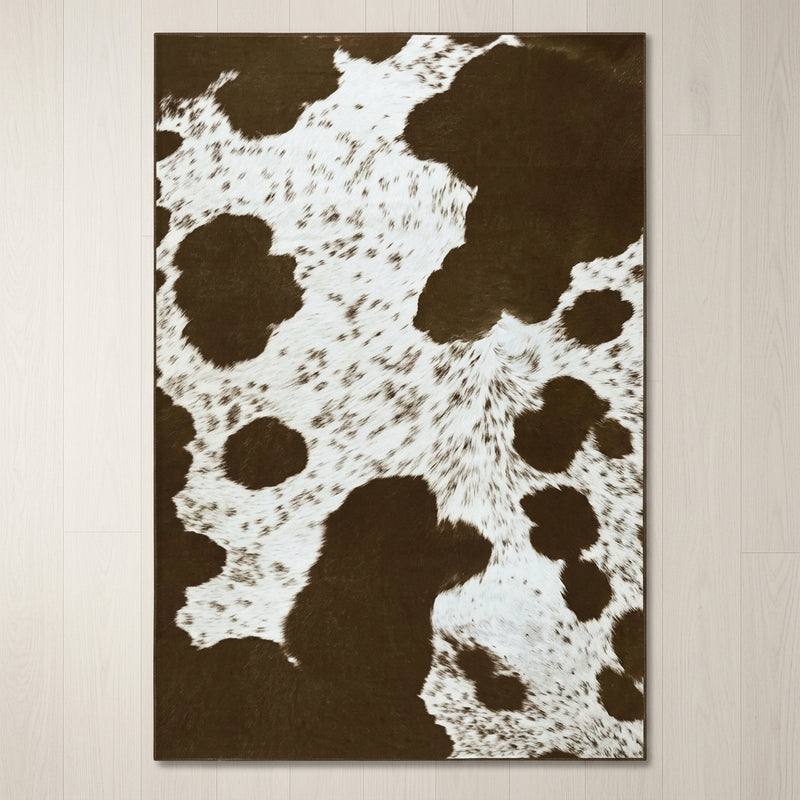 Faux cowhide rug in cow print styled under a leather sofa in a modern living room