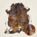 Faux cowhide rug in cow print styled under a leather sofa in a modern living room