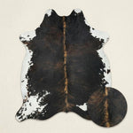 Faux cowhide rug in cow print styled under a leather sofa in a modern living room