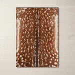 Faux cowhide rug in cow print styled under a leather sofa in a modern living room