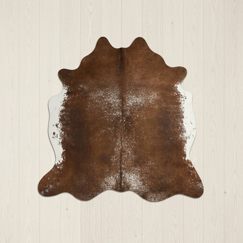 Faux cowhide rug in cow print styled under a leather sofa in a modern living room