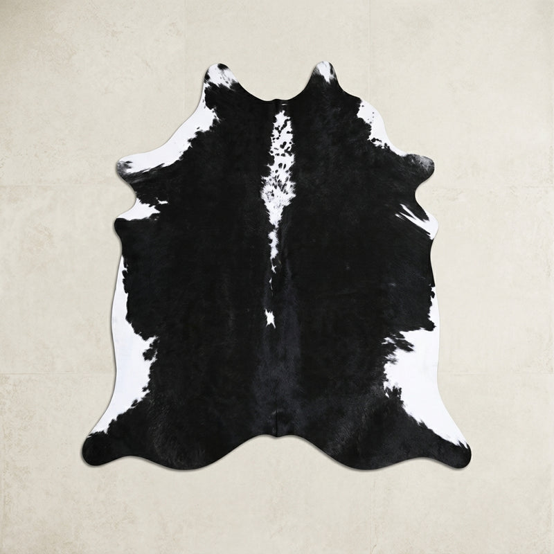 Faux cowhide rug in cow print styled under a leather sofa in a modern living room