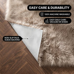 Faux fur area rug shown beside a bed, illustrating machine-washable, vacuum-or-shake-clean maintenance
