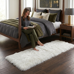 Ultra-soft faux sheepskin area rug in white placed in living room beside armchair