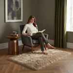 Ultra-soft faux sheepskin area rug in white placed in living room beside armchair
