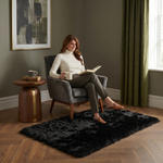 Ultra-soft faux sheepskin area rug in white placed in living room beside armchair