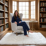 Ultra-soft faux sheepskin area rug in white placed in living room beside armchair