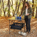 Woman setting drinks on an aluminum folding camping table outdoors