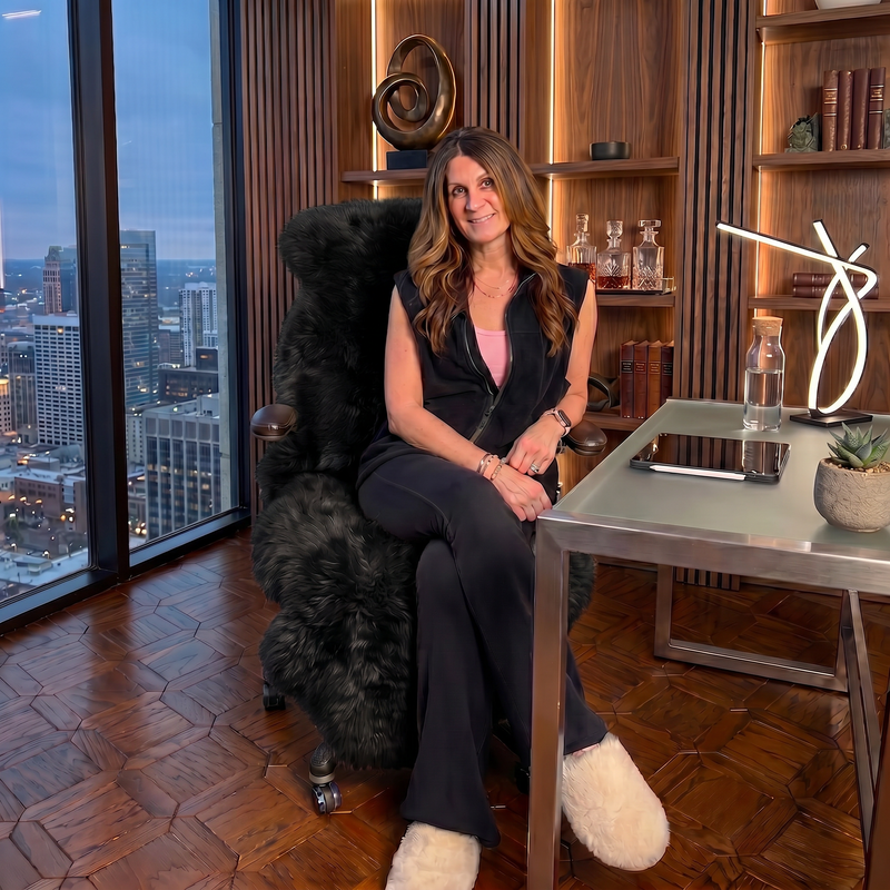 Tan genuine sheepskin rug draped over a modern office chair in a high-rise workspace