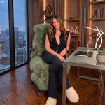 Tan genuine sheepskin rug draped over a modern office chair in a high-rise workspace