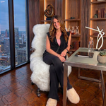 Tan genuine sheepskin rug draped over a modern office chair in a high-rise workspace