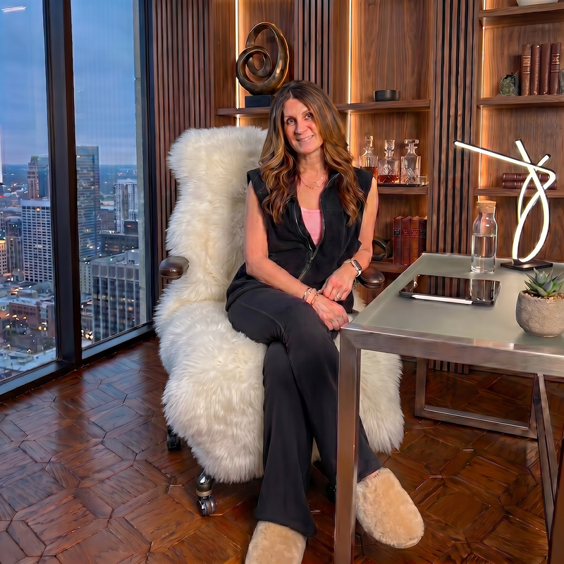 Tan genuine sheepskin rug draped over a modern office chair in a high-rise workspace