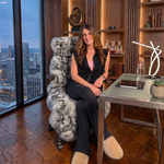 Tan genuine sheepskin rug draped over a modern office chair in a high-rise workspace