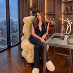 Tan genuine sheepskin rug draped over a modern office chair in a high-rise workspace