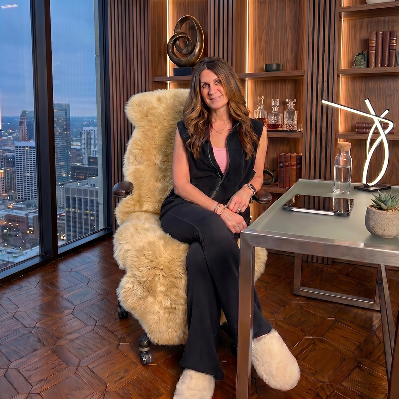 Tan genuine sheepskin rug draped over a modern office chair in a high-rise workspace