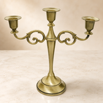 Gold three-arm metal candelabra candle holder on a white background