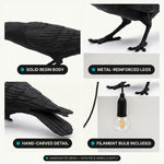 Four close-up details of the black raven lamp: resin body, metal-reinforced legs, hand-carved feathers, and the filament bulb held in its beak