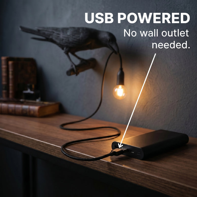 Black raven lamp on a wood desk connected to a USB power bank among vintage books and a magnifying glass