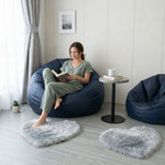 Pink heart shaped faux fur rug on a wood bedroom floor beside a bed
